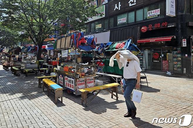 부산 중구 비프광장에서 한 시민이 햇볕을 가리기 위해 겉옷을 벗어 머리에 쓴 채 지나가고 있다. 2023.7.6/뉴스1 ⓒ News1 권영지 기자