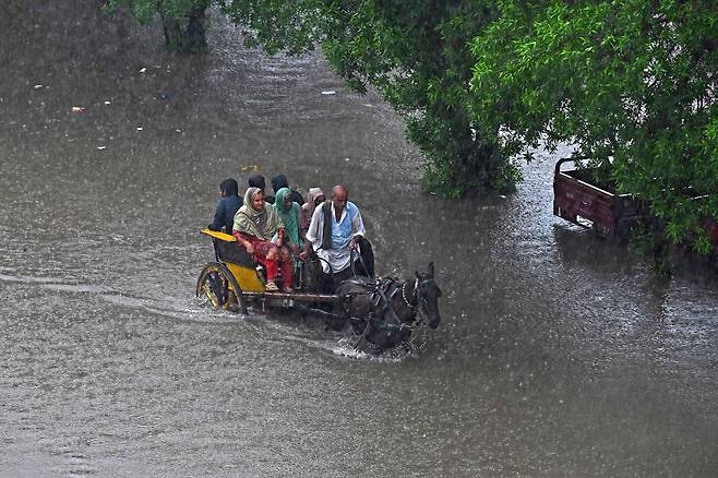 2023년 7월 5일 파키스탄 라호르에서 사람들이 폭우가 내려 침수된 거리를 마차를 타고 지나가고 있다./AFP 연합뉴스