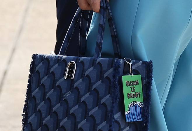 김건희 여사 가 든 ‘로사케이’ 가방에 ‘부산은 준비됐다(BUSAN IS READY)’라고 적힌 키링이 달려있다. (연합뉴스)