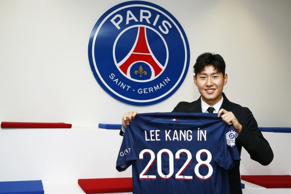 이강인이 9일 프랑스 프로축구 1부리그 파리 생제르맹(PSG)에 입단한 뒤 계약 기간 2028년과 자신의 이름이 새겨진 유니폼을 들어올리며  미소짓고 있다. {PSG 홈페이지 캡처]