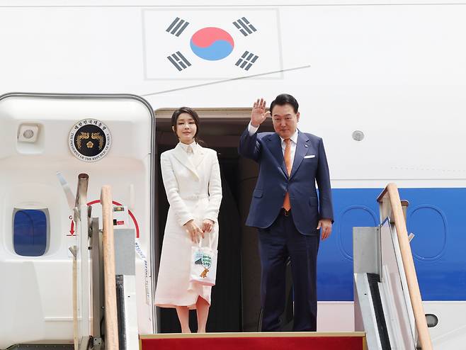 President Yoon Suk Yeol (right) waves before boarding Air Force One at Seoul Air Base in Seongnam, Gyeonggi Province, with first lady Kim Keon Hee on Monday. (Yonhap)