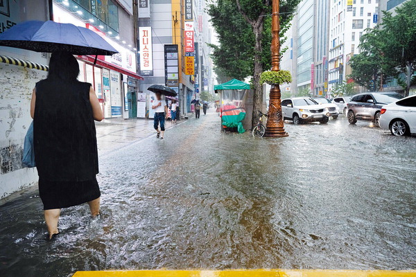 11일 오후 부산지역에 호우경보가 발효된 가운데 시민이 집중 호우로 침수된 연제구 연산교차로 거리를 걸어가고 있다.  전민철 기자 jmc@kookje.co.kr