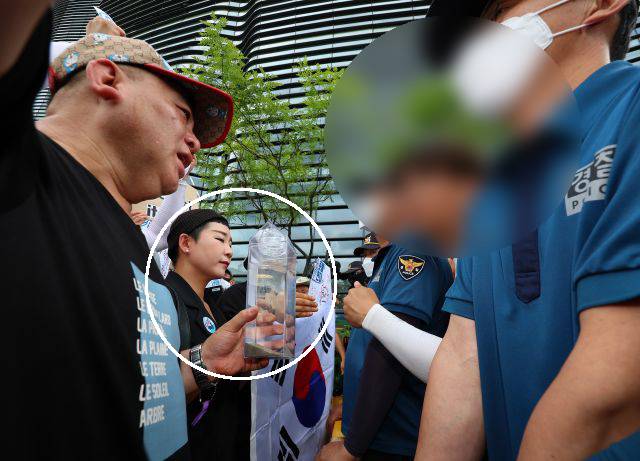 가수 리아(흰색 원)를 비롯한 촛불연대 회원들이 8일 서울 종로구 일본대사관에서 경찰과 대치하고 있다. 촛불연대는 직접 공수한 일본 후쿠시마 바닷물을 대사관 측에 전달하려 했지만 경찰에 제지당했다. 연합뉴스