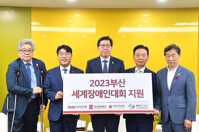 BNK부산은행이 11일 부산시청에서 2023 부산세계장애인대회 조직위원회에 후원금 1억원을 전달했다. 방성빈 부산은행장, 박형준 부산시장, 최금식 부산사회복지공동모금회 회장(왼쪽 둘째부터) 등이 후원금 전달식에서 기념촬영을 하고 있다. 부산시