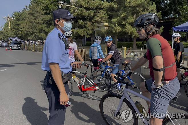 (AP=연합뉴스) 지난달 4일 중국 베이징 톈안먼 광장 앞에서 경찰이 자전거를 타고 가던 사람을 검문하는 모습.2023.7.13.