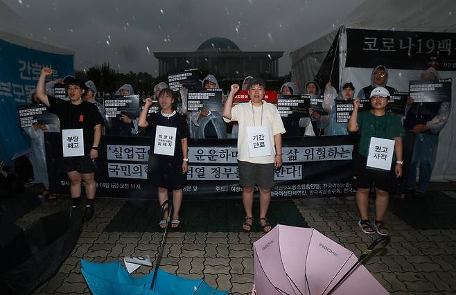 ‘실업급여’ 우산을 정부와 여당에 빼앗기는 행위극을 한 활동가들이 구호를 외치며 기자회견을 마무리하고 있다. 김혜윤 기자