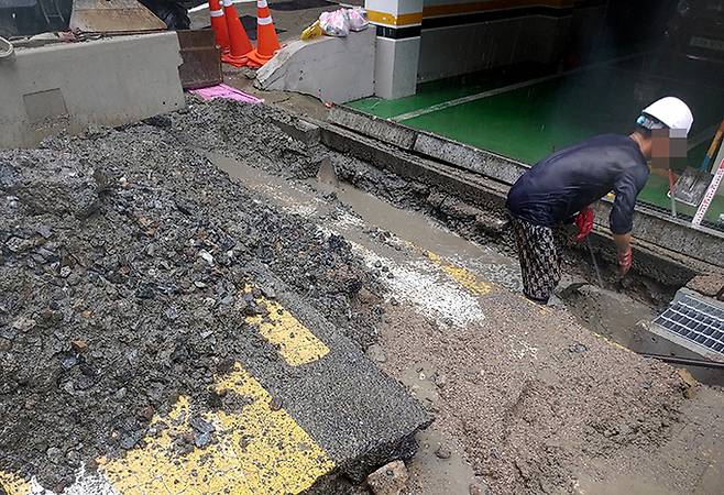 지난 13일 지난해 8월 일가족 3명이 참변을 당한 바로 앞도로에서 구청 관계자들이 빗물받이 응급 복구작업을 하고 있다.