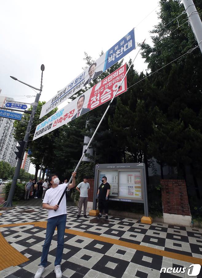 인천시 연수구 관계자가 12일 인천시 연수구 동춘동의 거리에 걸린 정당현수막을 철거하고 있다.  2023.7.12/뉴스1 ⓒ News1 정진욱 기자