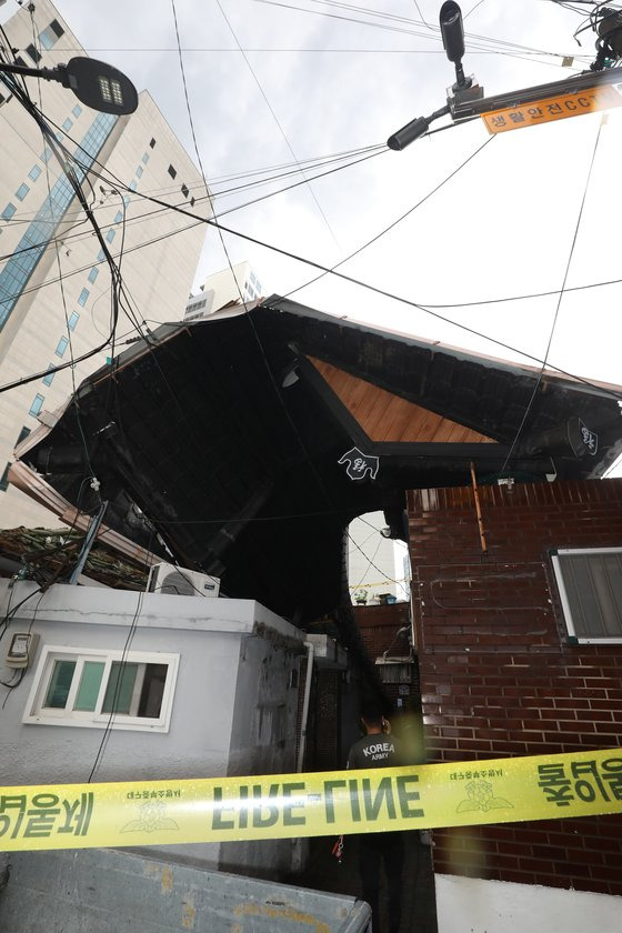 지난 11일 오후 대구 도심에 기습적인 폭우가 쏟아진 가운데 중구 남산동의 한 주택 지붕이 크게 파손된 채 옆집에 걸쳐 있는 모습을 주민들이 바라보고 있다. 뉴스1