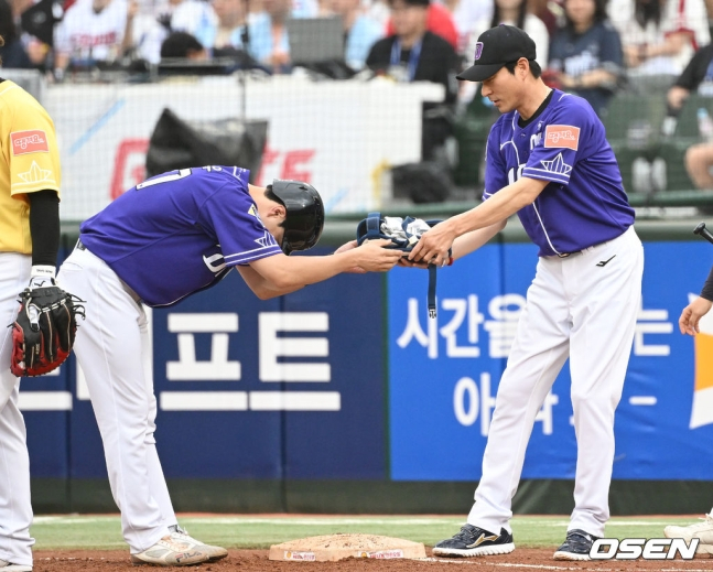 나눔 올스타 박건우(왼쪽)가 15일 부산 사직야구장에서 열린 2023 KBO 올스타전에서 1회말 안타를 치고 나간 뒤 강인권 1루 코치에게 90도 고개를 숙이며 장비를 전달하고 있다.