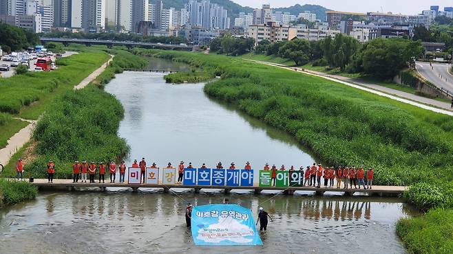 지난 12일 오후 2시 청주 서문대교 아래 무심천에서 사단법인 풀꿈환경재단 관계자들이 '미호강 미호종개야 돌아와'라는 글자의 팻말을 들고 서 있다. 이 단체는 이날 주민참여형 하천관리를 촉구하며 퍼포먼스를 했다. /풀꿈환경재단 제공