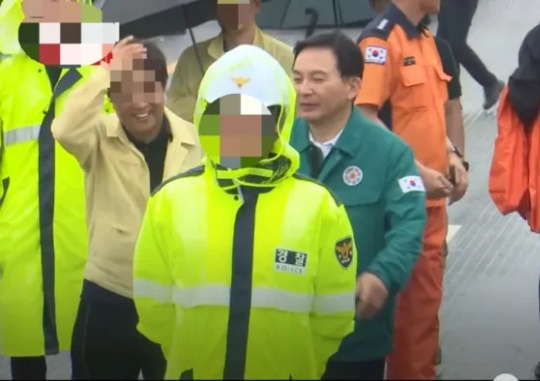 A senior public official from the Chungcheongbuk-do Provincial Office (left of picture) overseeing the management of underpasses, smiles next to Minister of Land, Infrastructure and Transport Won Hee-ryong, who visited the site of the accident, where an underpass was flooded leading to nine deaths in Osong, Cheongju in Chungcheongbuk-do. Captured from a video posted by the YouTube user nocutv