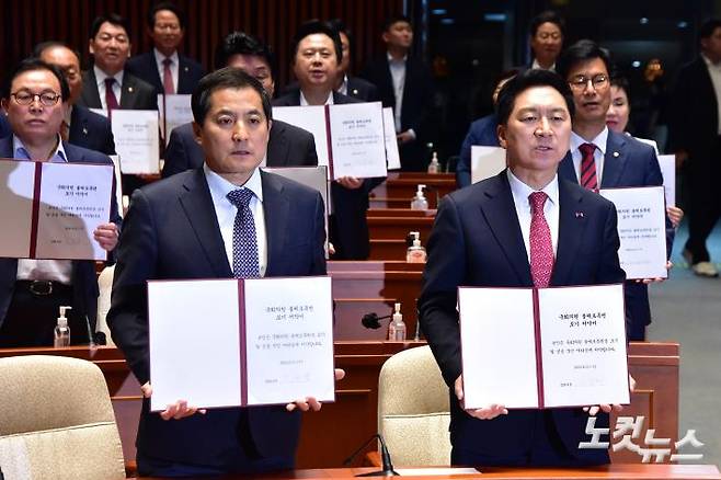 지난달 21일 국민의힘 김기현 대표, 윤재옥 원내대표 등 의원들이 서울 여의도 국회에서 열린 의원총회에서 '국회의원 불체포특권 포기 서약서'를 들어보이고 있다. 윤창원 기자