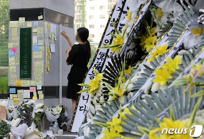 20일 오전 서울 서초구의 한 초등학교 앞에서 한 교사가 추모메시지를 써붙이고 있다. 서울시교육청 등에 따르면, 지난 18일 오전 이 학교 1학년 담임인 A씨(23)가 극단적인 선택으로 사망하는 일이 발생했다. 2023.7.20/뉴스1 ⓒ News1 구윤성 기자