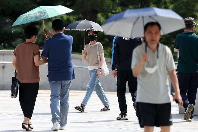 장마전선이 물러간 뒤 서울 지역 낮 최고기온이 33도를 넘어 폭염주의보가 발령된 19일 오후 서울 용산구 국립중앙박물관을 찾은 시민들이 양산을 펼쳐 따가운 햇볕을 피하고 있다. /뉴스1