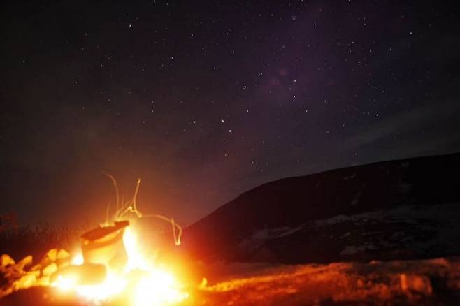 모닥불 너머 빛나는 별들 중 일부는 수백 광 년 이상 떨어진 거리에 있다. 그럼에도 별을 바라보는 사람의 시점으로는 모닥불도 별도 현재다. (러시아 캄차카, 2008 ⓒ허영한)