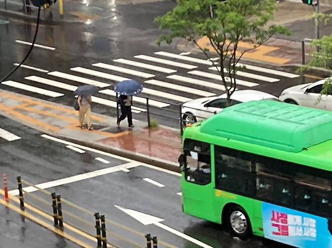 호우주의보가 내린 23일 우산을 쓴 시민들이 버스를 타기 위해 서울 서대문구 성산로 버스 정거장으로 향하고 있다. 사진=김경수 기자