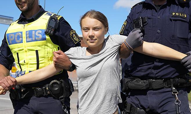 스웨덴 기후 운동가 그레타 툰베리가 24일(현지시각) 스웨덴 말뫼의 석유 시설 입구를 봉쇄한 혐의로 경찰에 연행되고 있다. 툰베리는 지난달 같은 곳에서 시위를 벌이던 중 교통에 방해가 된다는 이유로 장소를 옮기라는 경찰의 지시를 따르지 않은 '경찰 불복종' 혐의로 벌금형(약 30만 원)을 선고받은 지 불과 몇 시간 만에 다시 시위를 벌였다. AP뉴시스
