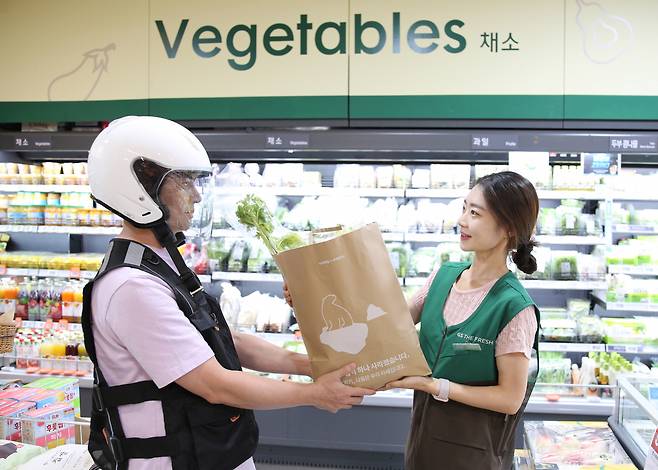 GS더프레시에서 직원이 퀵커머스 배달자에게 상품을 전달하고 있다. [GS리테일 제공]