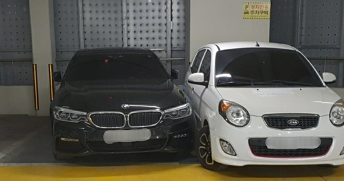 주차선을 넘어온 BMW 차량 옆에 경차가 주차돼 있다. BMW 차주는 차를 못 빼 경찰의 도움을 받았다. [출처=연합뉴스, 제보자 A씨 제공]