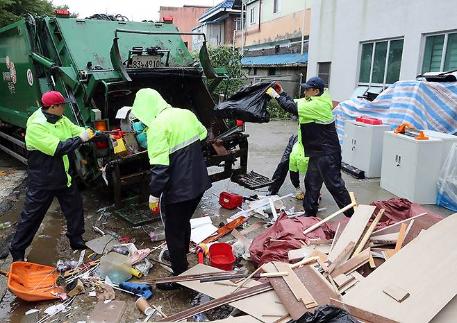 지난 18일 오후 충남 공주에 굵은 장대비가 내리는 가운데, 공주시청 직원들이 침수 피해로 못 쓰게 된 가재도구를 수거하고 있다. (사진=저작권자(c) 연합뉴스, 무단 전재-재배포 금지)