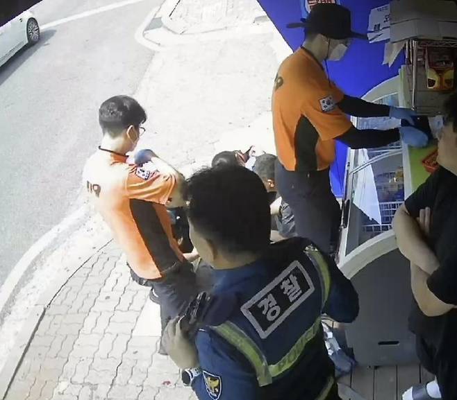 지난달 30일 한 여성이 편의점 앞에 고개 숙인 채 앉아있던 중년 남성에게 생수를 건넨 사연이 전해졌다. 위 사진은 편의점 CCTV 캡처본. [사진 = 보배드림 캡처]