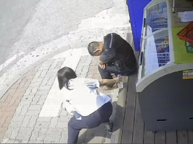 지난달 30일 한 여성이 편의점 앞에 고개 숙인 채 앉아있던 중년 남성에게 생수를 건넨 사연이 전해졌다. 위 사진은 편의점 CCTV 캡처본. [사진 = 보배드림 캡처]