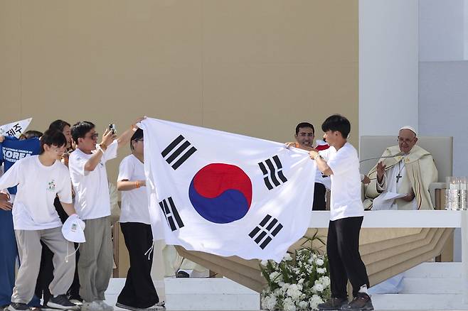 6일(현지시간) 포르투갈 수도인 리스본 테조 공원에서 열린 '가톨릭 세계청년대회' 폐막 미사에서 프란치스코 교황이 2027년 차기 대회가 서울에서 열린다고 발표하고 있다. 이에 한국 청년들이 무대에 올라가 태극기를 펼쳐 보이며 기뻐하고 있다.  AFP연합뉴스