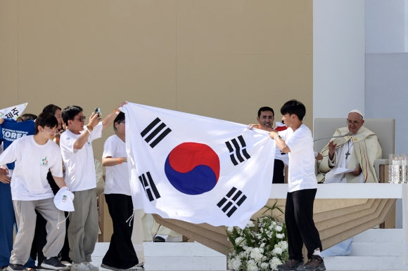 한국 가톨릭 순례자들이 6일(현지시간) 포르투갈 리스본의 테주 공원에서 제37회 가톨릭 세계청년대회를 마치면서 2027년 다음 대회 개최지로 한국 서울을 발표하자 태극기를 펼치며 자축하고 있다. 리스본 EPA 연합뉴스