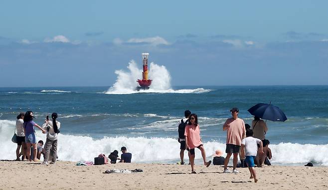 휴가지를 찾은 피서객들이 바다에 들어가지 못해 해변에서 발만 담그며 아쉬워하는 가운데 연꽃모양의 해운대APEC등표(등대)에 파도가 부딪히고 있다. /남강호 기자