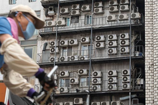 폭염 위기 경보 ‘심각’ 단계까지 발효될 정도로 연일 불볕더위가 이어지고 있다. 자전거를 탄 시민이 에어컨 실외기들이 설치된 서울의 한 건물 앞을 지나가고 있다. / 뉴스1