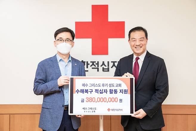 예수그리스도후기성도교회 김현수 장로(오른쪽)가 대한적십자사 이상천 사무총장에게 수재의연금을 전달하고 있다. /예수그리스도후기성도교회 제공