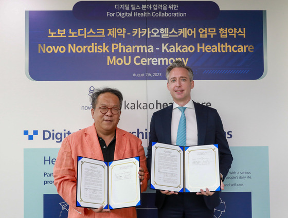 Kakao Healthcare CEO Hwang Hee, left, and Sasha Semienchuk, general manager of Novo Nordisk Pharma Korea, pose for a photo during a signing ceremony for a joint digital healthcare service at Novo Nordisk’s local office in southern Seoul, Monday. [KAKAO HEALTHCARE]