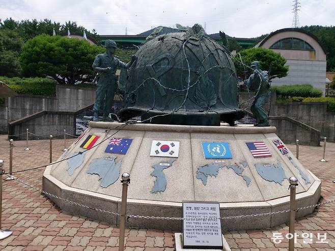 경남 거제의 포로수용소 유적공원에 유엔군 참전국 국기와 철모 조형물. 국군과 북한군이 철조망을 함께 걷어내 화합과 통일을 기원하는 마음을 담았다는 설명이 붙어있다. 거제 = 구자룡 기자