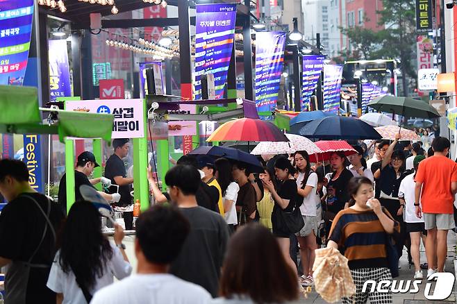 12일 오후 경북 포항시 중앙상가 실개천에서 열린 '2023포항중앙상가 야시장'에서 시민과 관광객들이 갑자기 내린 가을비에 우산을 들고 음식을 기다리고 있다.2023.8.12/뉴스1 ⓒ News1 최창호 기자