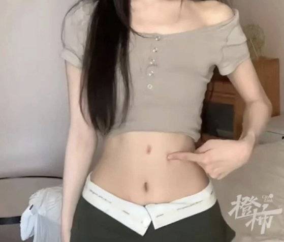 실제 배꼽보다 몇 ㎝ 위에 붙여서 다리가 길어 보이는 효과를 노리는 배꼽 스티커. 사진 QQ닷컴 홈페이지 캡처