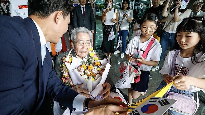 오성규 애국지사가 서울 김포공항에서 열린 환국 환영 행사를 마치고 어린이들에게 선물을 전달받고 있다. 뉴스1