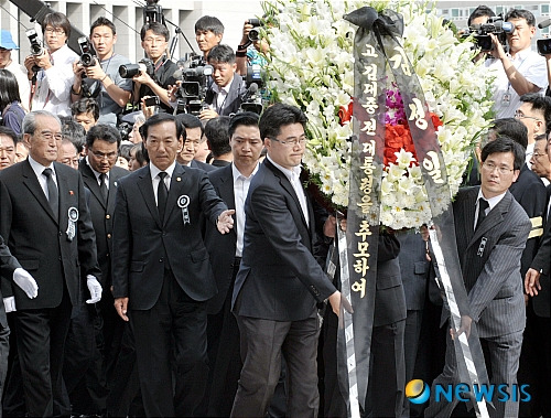 [서울=뉴시스] 사진공동취재단 = 2009년 8월21일 오후 고 김대중 전 대통령 서거 조문단으로 서울에 온 북한 노동당 김기남 비서와 통일전선부 김양건 부장이 김정일 위원장 이름의 조화를 국회분향소에 전하고 있다. photo@newsis.com