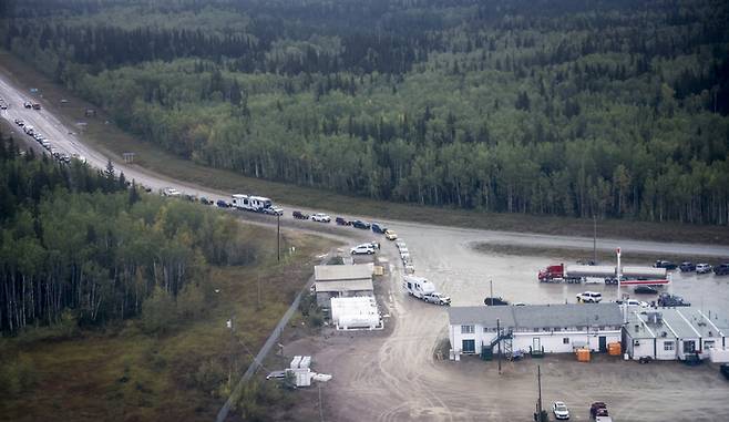 17일(현지시간) 캐나다 노스웨스트 준주의 주도 옐로나이프에서 빠져나온 차량들이 주유소에서 기름을 넣기 위해 긴 줄을 서고 있다. AP연합뉴스