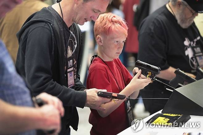 전미총기협회(NRA) 연례회의·전시회에서 아들과 총기를 살펴보는 남성.[연합뉴스]