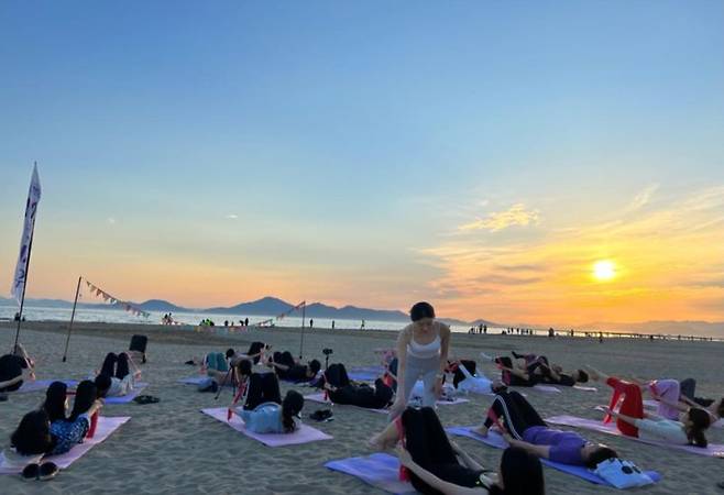 ▲2023 상반기 해양치유 프로그램의 '해변요가' 수강생들이 바닷가 모래사장에서 요가를 하고 있다. /사진=부산시