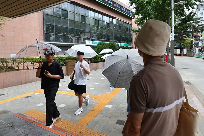 비가 내린 22일 서울 명동거리 지하상가 입구에서 우산이 없는 한 시민이 비를 피하고 있다. 연합뉴스