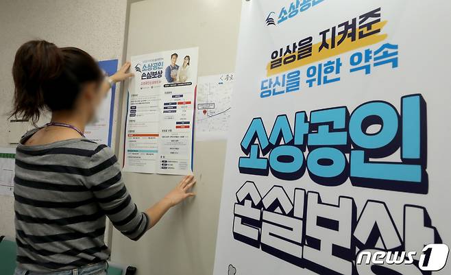 한 직원이 손실보상금 신청 안내문을 붙이고 있다./뉴스1 ⓒ News1 장수영 기자