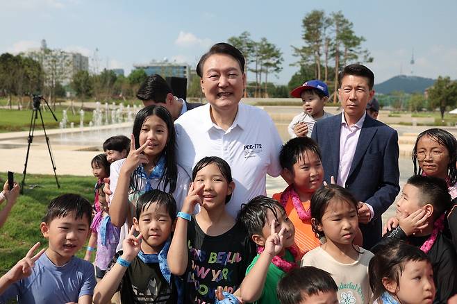 지난 26일 윤석열 대통령이 서울 용산어린이정원에 조성된 분수정원에서 열린 다둥이가족 초청 행사에 깜짝 방문해 어린이들과 기념촬영을 하고 있다. 윤 대통령은 이날 흰색 천안함 셔츠를 입었다.  대통령실