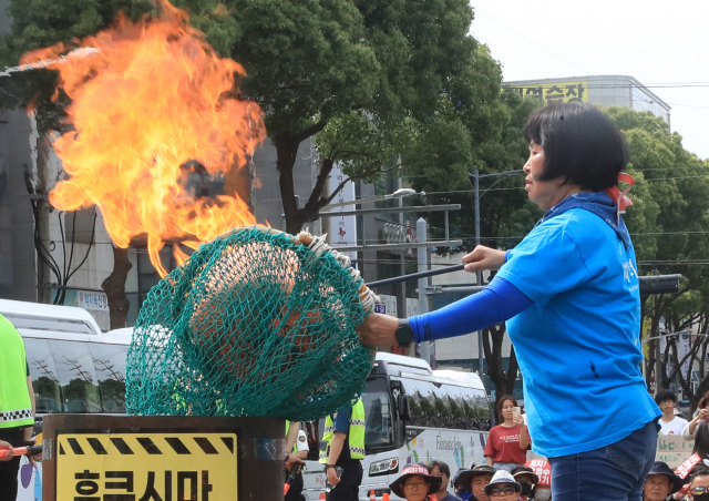 지난 6월13일 오후 제주시 노형오거리에서 열린 ‘일본 핵오염수 해양투기 저지 제주 범도민대회’에서 제주도해녀협회 고송자 사무국장이 항의 표시로 테왁(해녀 물질 기구)을 태우고 있다. 연합뉴스