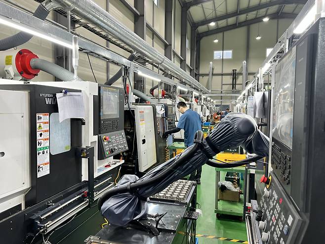 지난 29일 찾은 부산 기장군 정관신도시 우성정밀 공장에 설치된 두산로보틱스의 협동로봇 모습. 로봇 뒤로 현장 작업자가 가공기를 작동하고 있다. [김은희 기자]