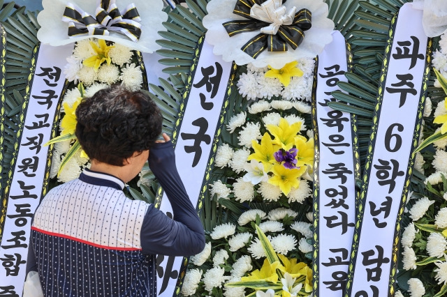 2일 오전 서울 양천구 소재 초등학교 앞에 마련된 숨진 교사 A씨의 추모공간에서 한 추모객이 눈물을 닦고 있다. 연합뉴스.