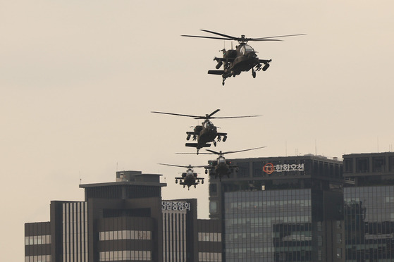 Multiple AH-64 Apache, twin-engine attack helicopters, fly over Myeong-dong in Jung District, central Seoul, on Monday as to practice for the military parade that will be held on Armed Forces Day on Oct. 1. This year marks the 75th anniversary of the founding of the Korean military. [YONHAP]