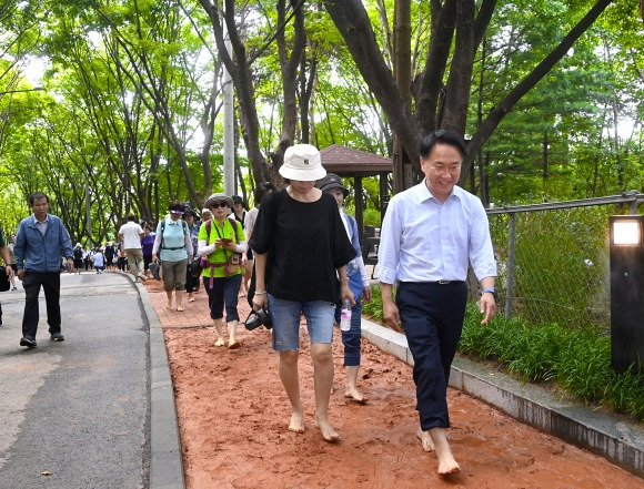 이성헌(오른쪽) 서울 서대문구청장이 지난달 17일 개장한 안산 황톳길에서 맨발로 걷고 있다. 서대문구 제공