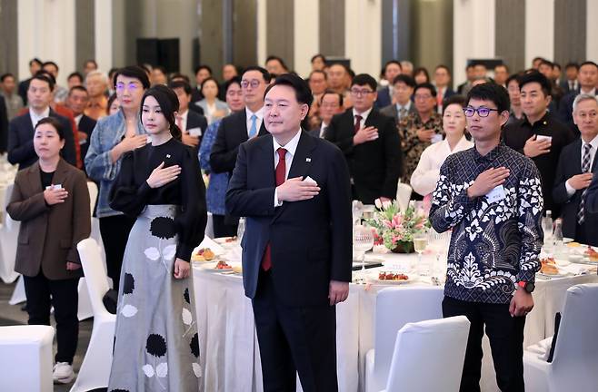 아세안(동아시아국가연합) 정상회의 참석차 인도네시아를 방문한 윤석열 대통령과 부인 김건희 여사가 5일(현지시각) 자카르타 시내 한 호텔에서 열린 동포 초청 만찬 간담회에서 국기에 대한 경례를 하고 있다./뉴시스